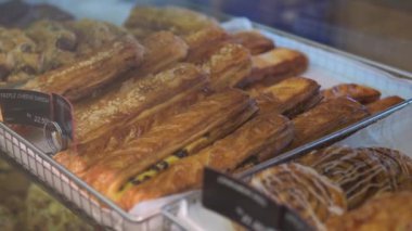 View on bakery counter with many different cakes, sandwiches and bread displayed, freshly baked pastries on a bakery shop counter. Baked baguettes and pies on showcase in bakery shop.