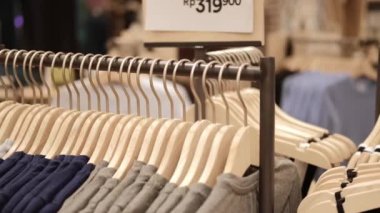 Close-up of hangers with clothes in a store, clothes for sale hang on wooden hangers, a new collection of clothes in different sizes. Industry in the field of clothing trade of famous brands.