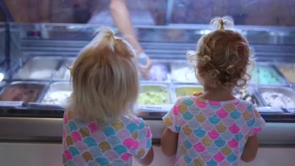 ビーガンストアで子供のためのアイスクリームを購入します 2人の幼児が甘い御馳走を待っているアイスクリームカウンターに立っています 子供の頃から砂糖や動物性乳を使わない適切な栄養の概念 — ストック動画