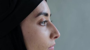 Close-up profile of the face of an Arab woman in a black hijab. An Islamic world that professes Islam and forces women to cover their hair with a scarf from other peoples views in their direction.