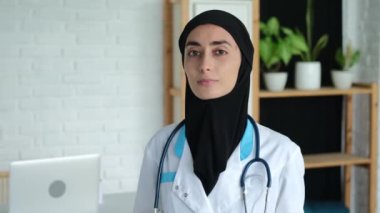 In the hospital office, a Muslim woman doctor in a hijab is receiving a woman looking at the camera.Treatment in the Islamic world. A woman can choose a job for herself and benefit people.