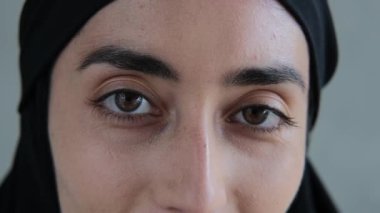 Siyah tesettürlü doğulu bir kadının gözlerine yakın çekim. Kadın çerçeveye dostça gülümsüyor. Şeriat kurallarına göre yaşayan bir Arap kadını. Kahverengi gözlü kadın.