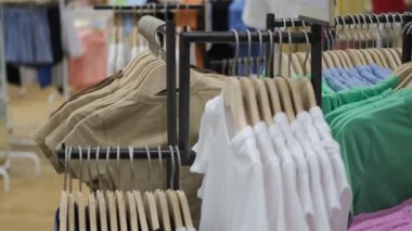 Sale of clothes of various brands in the store a new collection of clothes for women and men. The store has dresses and t-shirts on the shoulders in different sizes and colors.