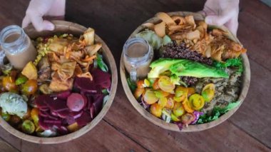 Two wooden plates with mouth-watering dishes of vegetables and herbs are placed on a wooden table. Eco vegetarian restaurant takes care of all living beings on the planet. Vegan food in the restaurant