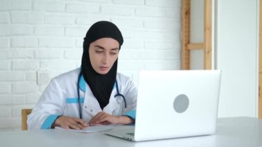 A woman in a hijab is undergoing online training to improve her qualifications as a doctor. Medical education in Muslim countries. The future doctor is recording a lecture on treatment.
