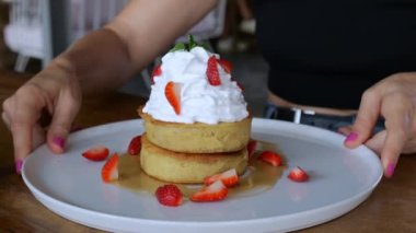 The woman turns the dish in different directions. On the plate is a delicious cake with berries and cream. Dessert created for a person who does not consume sugar