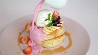 Close-up of an appetizing breakfast of sweet pancakes with fruits and berries poured over with a delicious cream. On top of the fritters is a ball of ice cream. Sweet morning mood.