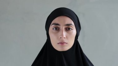 Kameraya bakan siyah tesettürlü Müslüman bir kadının portresi. Tüm hayatını İslami bir ülkede yaşayan, kadınların özgürlüğünü kısıtlayan Şeriat kanunlarıyla yaşayan çaresiz bir kadının bakışı..