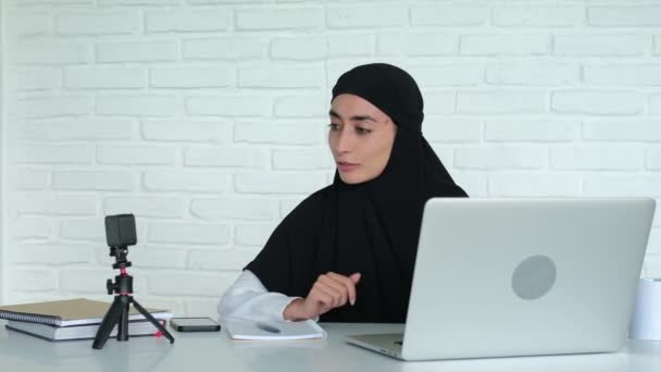 一位长相漂亮的阿拉伯女性博主通过网络摄像头与她的订户交流 一名头戴头巾的穆斯林妇女流连忘返 要求订阅并喜欢这个频道 — 图库视频影像