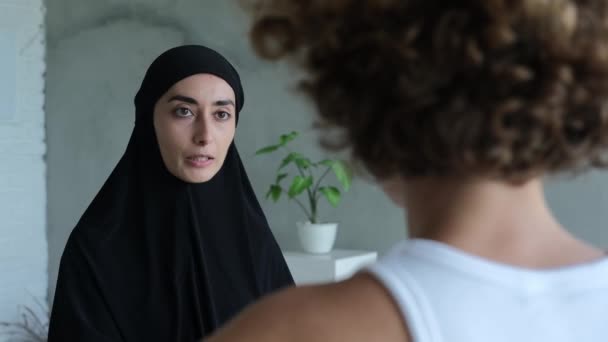 一名头戴头巾的穆斯林妇女向一名欧洲妇女讲述了伊斯兰教法的规定 一个基督徒和一个穆斯林女人之间关于这个世界上一个女人的正义和目的的争论 — 图库视频影像