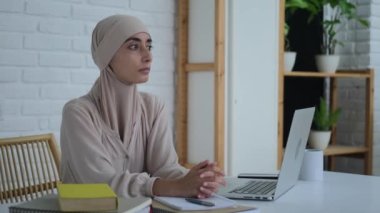 A beautiful woman in a hijab makes a career in the office. Womens rights in the Islamic world. A Muslim woman works at a computer looking to the future where everyone is equal. 