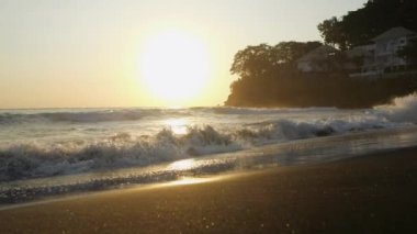 Evening sunset on the ocean. Nearby on the hill there are houses for tourists. To wake up and fall asleep to the sound of the surf. The concept of comfortable rest during travel.