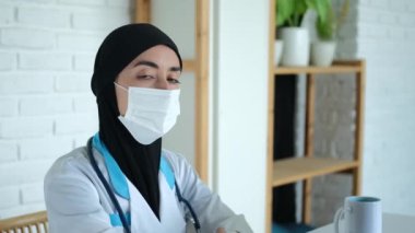 Maskeli Müslüman kadın doktor kameraya bakıyor. Arap dünyasında kadınlar için bir hastanede çalışmak. İş yerinde siyah peçeli ve tıbbi önlüklü bir sağlık görevlisi..