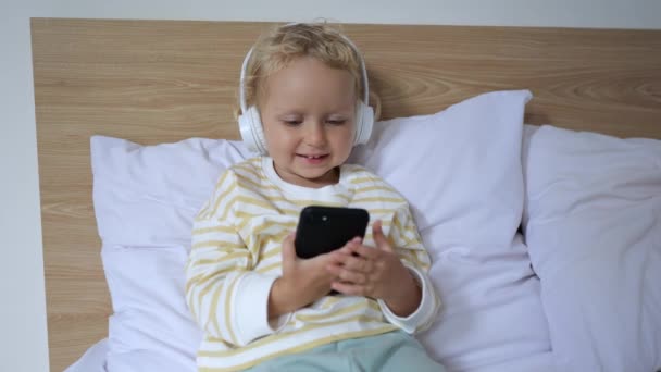 Small Child Sits Bed Watches His Favorite Cartoons His Smartphone — Vídeo de stock