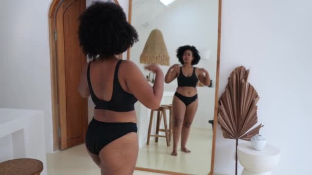 接受一名非洲裔亚洲妇女肥胖 一个穿着黑色内衣裤的黑人女人在镜子前看着她华丽的身躯 她的身体很喜欢她 身体正性的概念 — 图库视频影像