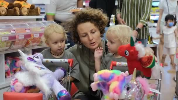 Молода Мати Відвідує Дитячий Магазин Величезною Кількістю Іграшок Дочками Близнюками — стокове відео