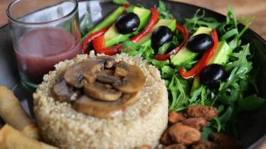 Siyah tabakta tabak: Kızarmış mantarlı haşlanmış pirinç, avokado salatası, dolmalık biber, zeytin, kişniş. Kızarmış badem. Küçük bardakta dut püresi. Lezzetli, besleyici yemeklere yakın çekim.