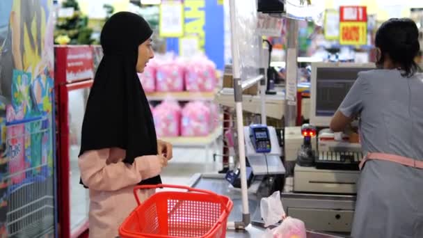 チェックアウトのヒジャーブの若い女性はリンゴを購入し ハイパーマーケットの従業員とかなり通信します キャッシャーはリンゴのウブド インドネシア 2022を計量することでお客様に優雅にサービスを提供します — ストック動画