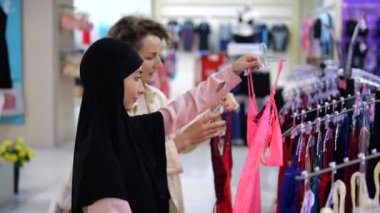 Alışveriş merkezindeki iki bayan arkadaş iç çamaşırı seçip alıyor. Farklı milletlerden iki kadının arkadaşlığı. Bir kadın giyim mağazasından seksi pembe ve kırmızı iç çamaşırları alan iki kadın..