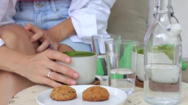 Kahvaltı: yeşil lezzetli aromatik kibrit çayı ve tabakta yulaf ezmeli kurabiye. Beyaz kıvırcık saçlı kadın dışarıda kibrit çay içiyor ve sabah havasının tadını çıkarıyor. Doğada nefis bir kahvaltı.