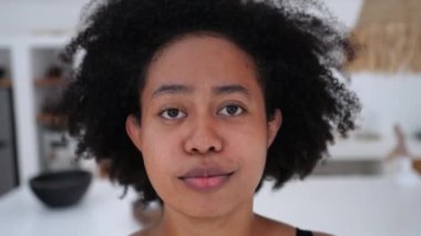 Yakın plan, kameraya mutlu bir şekilde gülümseyen çok uluslu, etnik çeşitlilikte çekici siyahi bir kadının yüzü. Genç milenyum kadını dişleriyle gülümsüyor. Kadın kendisi olmaktan gurur duyuyor ve mutlu.