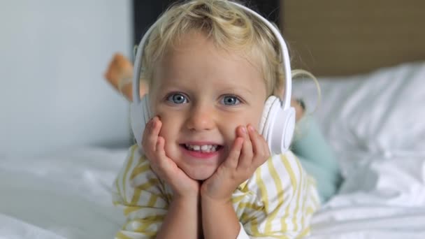Roztomilá Běloška Usměje Směje Posteli Sluchátky Naslouchajícími Hudbě Baby Girl — Stock video