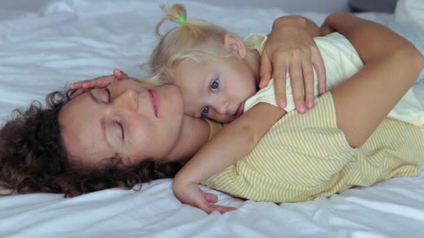 ママと娘の居心地の良い居心地の良い抱擁ベッドの上に横たわる 彼女は母親に嘘をついた 昼間の睡眠 母親と子供の愛情深い関係の概念 ママ抱擁彼女の赤ちゃん女の子タイト — ストック動画