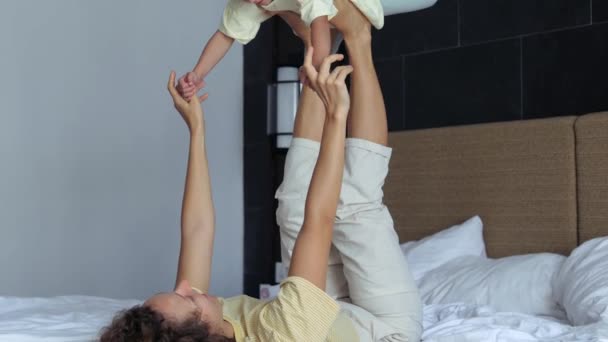 Mulher Mãe Deita Cama Com Pernas Levantadas Mantém Pequena Criança — Vídeo de Stock