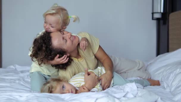幸せな子供たちを愛する母親が一緒にベッドの上で休んでいる抱擁 子供たちは母親をしっかりと愛し抱擁します かわいい愛情のある子供 娘と幸せな母親の子育ての概念 — ストック動画