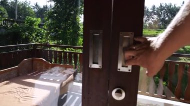 Kapalı Adam ellerini balkona uzatarak geniş bir pencere açar Tropikal Bahçe 'nin güzel manzarasıyla geniş bir pencere açar büyük bir pencere eve çok fazla ışık ve neşe getirir otelin büyük penceresinden güzel bir manzara