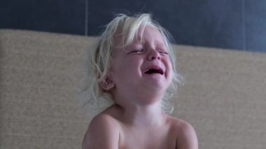 Küçük, üzgün, savunmasız çocuk hıçkıra hıçkıra ağlıyor acıdan ya da üzüntüden. Küçük bir çocuğun hayatında mutsuzluk, acı, keder. Üzgün mutsuz çocuğun yüzünde acı gözyaşları. Çıplak çocuk hıçkırarak ağlıyor..