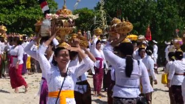 Ubud, Endonezya - 22 Ekim 2022: Balili kadınlar sahilde tanrılara meyve sunuyor, Bali tanrılarına saygılarını sunmak için adanın kutsal bayramını kutluyorlar..