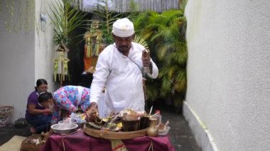 Ubud, Endonezya - 22 Ekim 2022: Bali 'de bir adak adama töreni. Papaz adak adadı adak adadı adadı adak adadı Balili tapınak rahibi yerel tören kıyafetleri içinde tanrılarına dua okudu