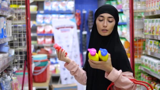Молодая Женщина Хиджабе Держит Руках Несколько Пакетов Косметических Жидкостей Внимательно — стоковое видео