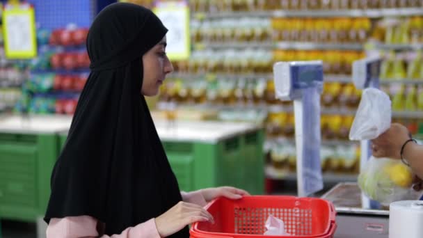 Wanita Muda Muslim Berdiri Dekat Meja Dengan Skala Dengan Keranjang — Stok Video