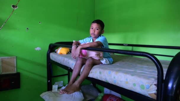インドネシアのウブド 2022年10月22日 孤独な少年孤児がシェルターの二段ベッドに座っている様子 孤児院での孤児の貧しく困難な子供時代は 親も友人もいない サドシェルターライフ — ストック動画
