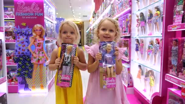 インドネシアのウブド 2022年10月22日 双子の女の子は人形バービーを選び 両親にこれらの玩具を購入するように頼みます おもちゃ屋で人形と幸せな子供たちのワイドショット コンセプトは子供を幸せにする おもちゃ店で人形を買う — ストック動画