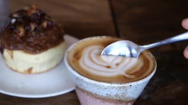 Çay kaşığıyla nefis, havadar kahve köpüğü kepçelerinin sinematik videosu. Badem sütlü ve kek arkaplanlı nefis kahve lattesinin sinematik videosu. Lezzetli bir öğle yemeği için kahve söyle. 