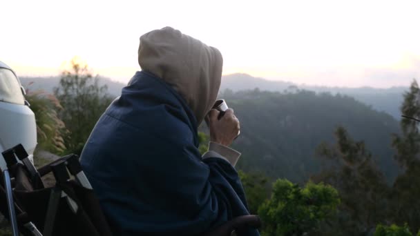 黎明时分 在可以俯瞰森林的野营拖车旁 寂寞地坐着喝着一大杯咖啡的女人 野营拖车上的免费生活通过野生动物景观旅行 野营预告片的概念旅行 — 图库视频影像