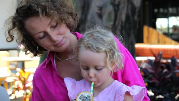Mãe Tem Filha Nos Braços Que Bebe Batido Tropical Saudável — Vídeo de Stock
