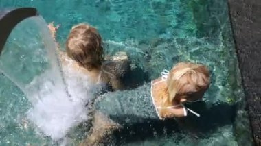 İki kızın çeşmenin altında dinlenip su masajının keyfini çıkardıkları yakın plan. Güneşli sıcak bir günde çeşmenin altında yüzen kızların su masajıyla rahatladıkları sinematik bir video. Su masajı kavramı