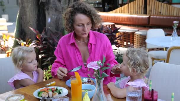 在家庭咖啡馆里带着学龄前女儿的年轻母亲给孩子们提供美味 健康的食物 广博的视野 夏季家庭咖啡馆 有美味的食物和健康的饮料 花时间和孩子们在家庭咖啡馆里 — 图库视频影像
