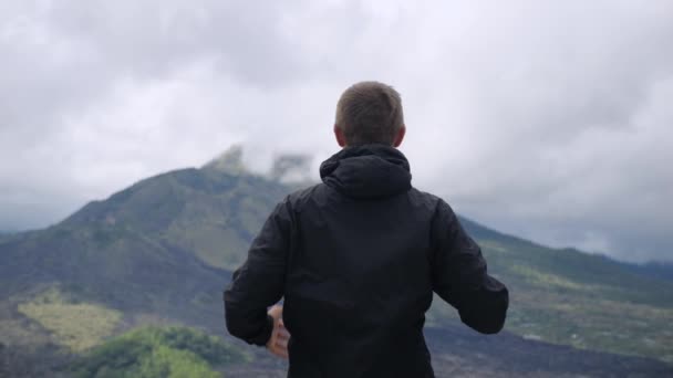 Millennial Man Bergstopp Tar Bort Huva Höjer Händerna Mot Himlen — Stockvideo