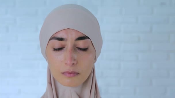 悲しいイスラム教徒の女性は彼女の目を下げ 明るいヒジャーブのイスラム教徒の女性の閉鎖は 彼女の手で彼女の顔を隠し 白い壁に向かって叫びます 泣くことを恥ずかしくないで ネガティブな感情が出てくる — ストック動画