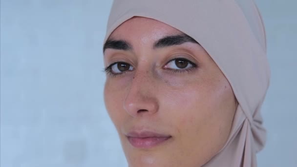 カメラで優しく見ている美しいムスリム女性 クローズアップ 明るいヒジャブを身に着けている若いイスラム教徒の女性の魅力的な肖像画は 優しく私たちを見ています コンセプト イスラム教徒の子供の優しい視線の魅力的な力 — ストック動画