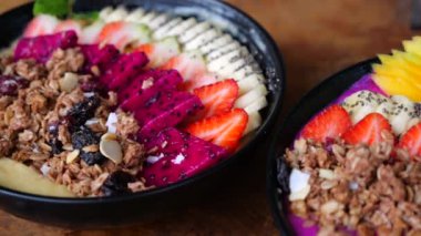 Muzlu, ejderha meyveli, tahıllı, çilekli, mangolu iki smoothie kasesi. Smoothie Bowl Şöleni 'nin sinematik videosu sağlıklı bir hoşgörüye davet ediyor. Taze, canlı meyve suyu kasesi Detaylı olarak zevkli