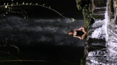 Şelale yakınlarındaki meditasyonda zihinsel sağlığını geri kazandıran dikey video. Ruh sağlığını su yoluyla düzelten kadının sinematik videosu. Fikir: akıl sağlığını korursan kendini harika hissedersin.