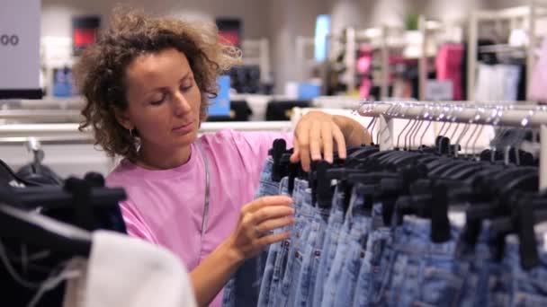 Snygg Kvinna Kommer Shopping Och Väljer Kläder Butiken Kvinna Tillbringar — Stockvideo