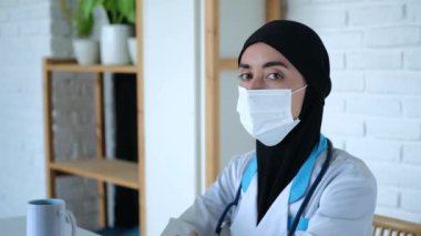 Maske takan ve tesettürlü dini bir sağlık görevlisi. Bakışları, insanların çektiği acıları çok iyi anladığını gösteriyor. Bakışlarında şefkat, bilgelik ve tıbbi yetenek var. Kadın bakışlarının derinliğini kavra