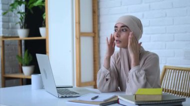 Başı ağrıyan tesettürlü Müslüman iş kadını yorucu bir iş nedeniyle baş ağrısı çekiyor. Baş ağrısından korunmak için ofis masajındaki genç müslüman bayanın geniş açılı görüntüsü. İş yerinde baş ağrısından kaçınmak için ağrı kesici kullan.